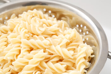 Colander with tasty fusilli pasta, closeup