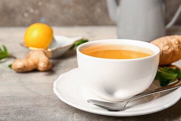 Cup of tea with spoon and ginger on grunge table, closeup