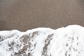 Fototapeta na wymiar Sea surf on the seashore on the sand. Sea foam on the sand.