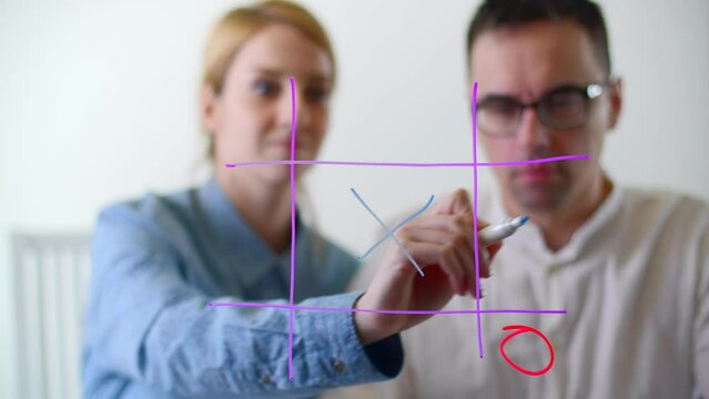 Coworkers resting while playing game on a glass board. Man and woman wearing office looks having a break from work. High quality 4k footage