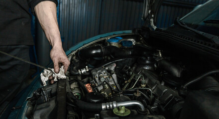 Mechanic checking car engine oil with dipstick