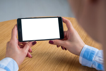 Mockup image: woman looking at black smartphone with white blank screen. Close up view of woman hands with smart phone mobile device. Mock up, copyspace, template and technology concept