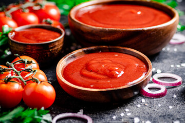 Tomato sauce in a wooden plate with onion rings and herbs. 