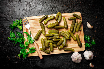 Pickles on a cutting board with garlic and parsley. 