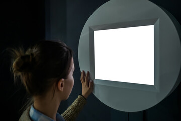 Woman looking at blank digital interactive white display wall at exhibition or museum with...