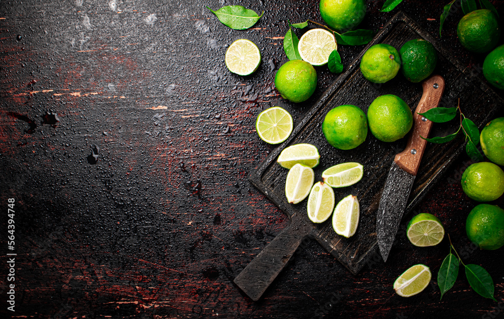 Wall mural Sliced lime with leaves on a cutting board with a knife.