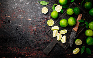 Obraz na płótnie Canvas Sliced lime with leaves on a cutting board with a knife.