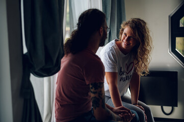 Obraz premium Couple sitting near the window in the bedroom at home
