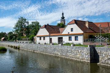 Obraz premium Old buildings and church tower on the river embankment in Soběslav, Czech Republic.