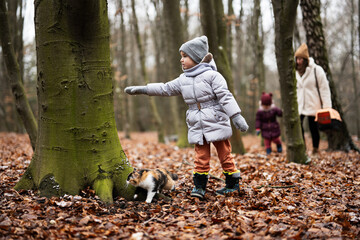 Mother and daughters walking with cat travel plastic cage carriage outdoor at wood.