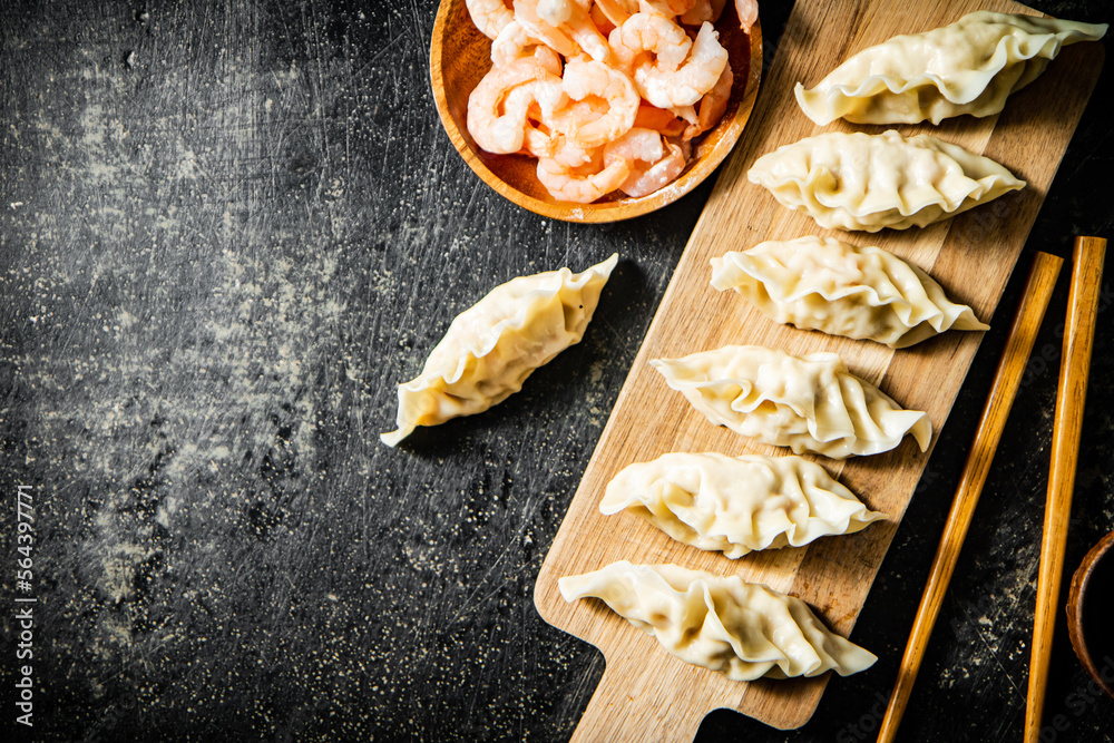 Poster dumplings gyoza with shrimp on a cutting board.