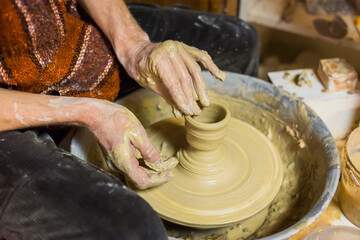 Professional male potter making ceramics on pottery wheel in workshop, studio. Close up view of potter hands. Handmade, art and handicraft concept