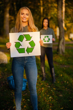 Smiling woman holding recycling symbol placard togheter with her team