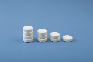 White placebo pills on blue background. Reducing medication intake and reducing dependence on...