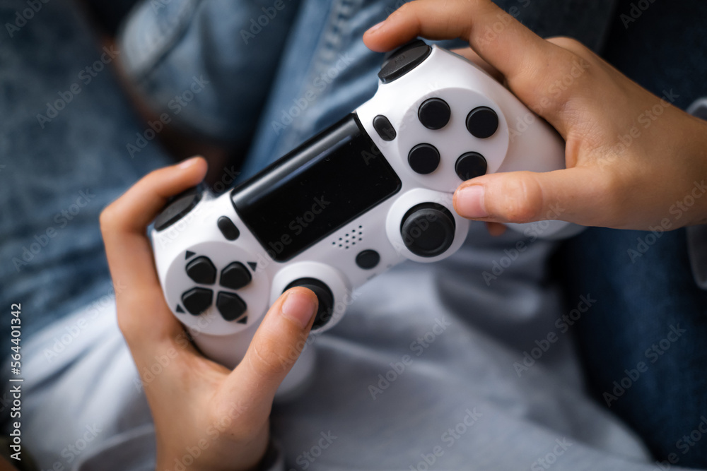 Wall mural kids hands with joystick, child playing video game console while sitting at home, real people, leisure concept.