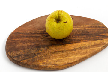 Yellow apple on wooden chopping board on white background isolated