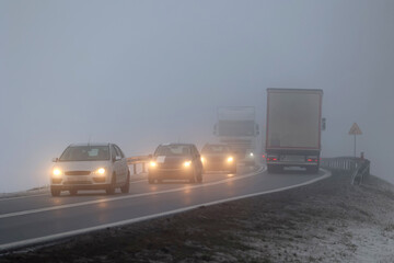Ruch pojazdów w gęstej mgle na drodze wieczorem. Niebezpiecznie.