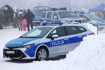 Radiowóz polskiej policji na zaśnieżonym parkingu w czasie akcji. 