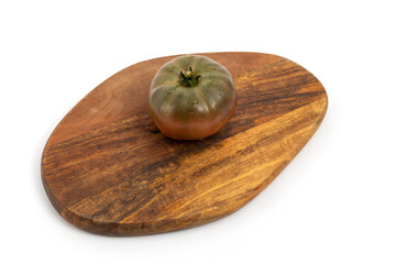 Black tomatoes on wooden chopping board on white background isolated