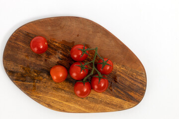 Cherry tomatoes on wooden chopping board on white background isolated