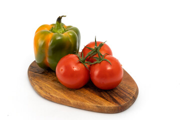 Pepper and cherry tomatoes on wooden chopping board on white background isolated