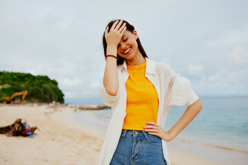 Portrait of a happy woman smile with teeth with long hair brunette walks on the sea beach summer travel and feeling of freedom, balance