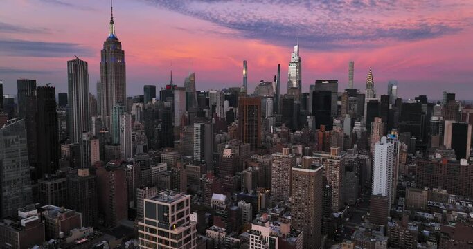 Establishing shot of iconic New York City buildings in midtown during bright red and pink sunset