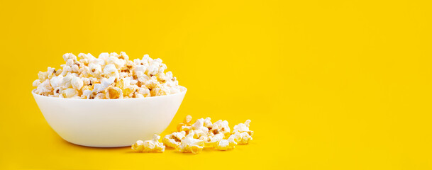 Scattered tasty cheese popcorn in bowl isolated on yellow background. Wallpaper, banner, header...