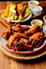 
Chicken wings. Buffalo chicken wings. American cuisine of chicken wings deep-fried, dipped in buffalo sauce made of vinegar,  cayenne hot sauce and butter. Served with celery, carrots, blue cheese.