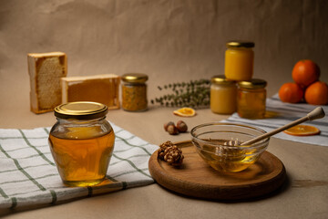 A glass jar with honey and a wooden stick in the background. Craft honey products.
