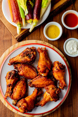 
Chicken wings. Buffalo chicken wings. American cuisine of chicken wings deep-fried, dipped in buffalo sauce made of vinegar,  cayenne hot sauce and butter. Served with celery, carrots, blue cheese.