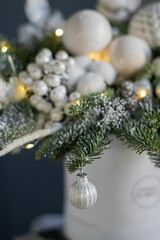Beautiful winter Christmas floral composition of fresh Nobilis in hat box in blue backgraund. Cotton, spruce, sparkling ornaments. Holiday concept. Happy New Year decorations.
