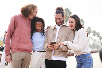 Group of happy friends using phone outdoors while walking al laughing. High quality photo