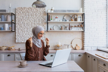 Freelancer in hijab working on laptop remotely from home, woman received good news and good news...