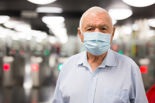 Portrait of senior caucasian man in face mask standing at entrance to metro station.