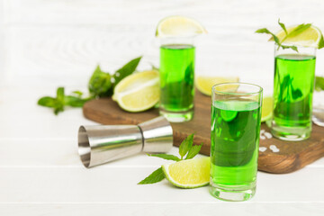 Sweet refreshing mint liqueur, with ice and mint leaves on table background, Shots with lime slice and mint flat lay