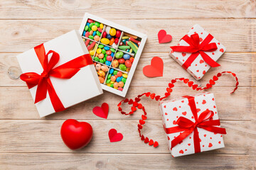 Valentine day composition: sweet candy, with gift boxes with bow and red felt hearts, photo template, background. Top View with copy space