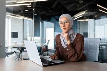 Portrait of a young woman Arab female student in hijab sitting in the office at the table and...