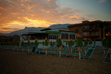 Paid beach with sunbeds and umbrellas at sunset.