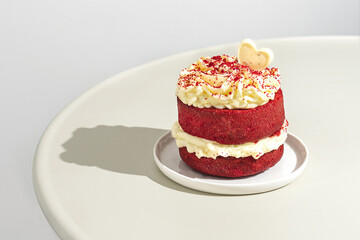 Valentine's day concept. Red velvet cake with white chocolate heart decoration. Hard shadows.
