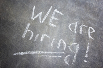 Fototapeta premium Text We are hiring handwritten with white chalk on a blackboard