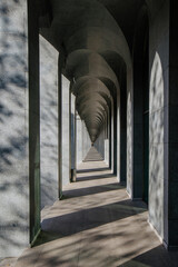 Long abstract unlimited corridor with rows of columns in sunlight