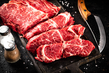 Raw beef on a cutting board with a knife. 