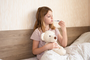 children get sick, girl measures temperature with a thermometer. cute girl sick at home in quarantine