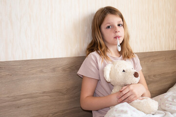 children get sick, girl measures temperature with a thermometer. cute girl sick at home in quarantine