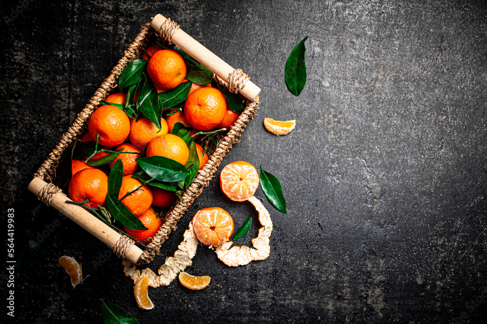 Poster Ripe tangerines with leaves in a basket. 