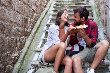 Happy couple eating pizza and smiling