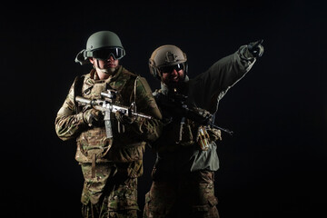 two soldiers in military uniform with weapons in a special operation at night, special forces attack against a dark background, elite troops