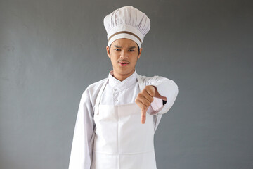 Male chef wearing kitchen uniform doing dislike sign after looking at culinary dinner meal. Cheerful woman chef showing thumbs down gesture
