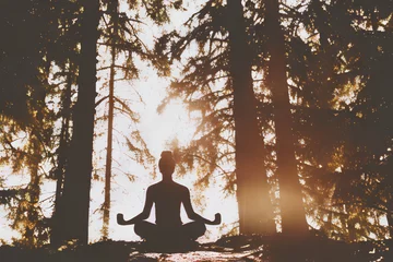Tissu par mètre  Silhouette of seated person meditating in front of the sun in the forest. Generative AI  © CarloAndr